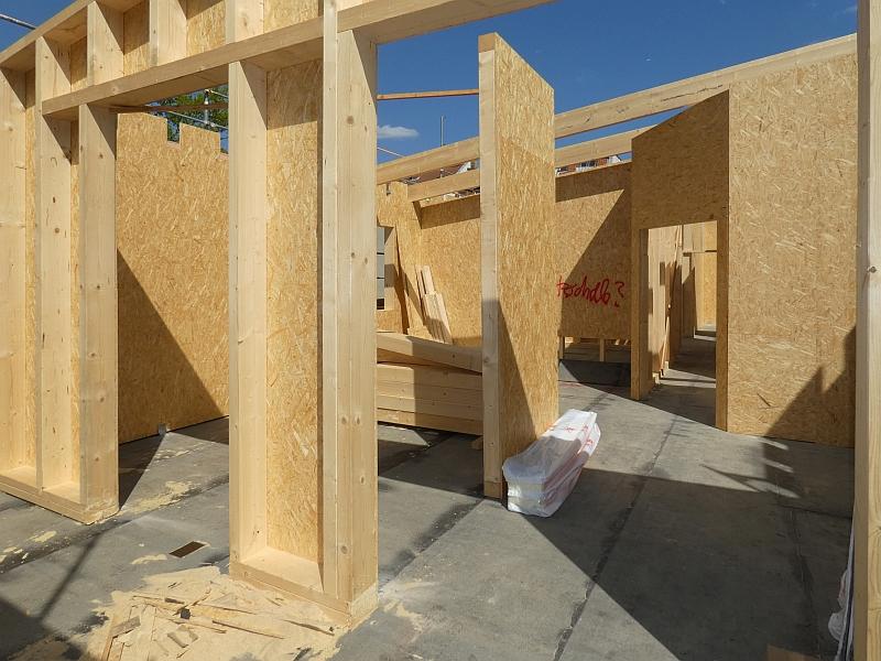 Auf dem Bild blickt man in eine Dachgeschosswohnung. Die wird aus Holz errichtet. Sie steht auf einem kleinen Gebäude.