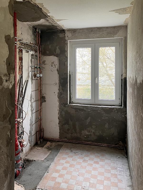 Das Bild zeigt einen leeren Raum. Im Raum wurden Wände abgerissen. Es wurden Löcher verschlossen. Neue Wasserleitungen sind zu sehen. Der Raum gehört zu einer Wohnung in Leipzig.
