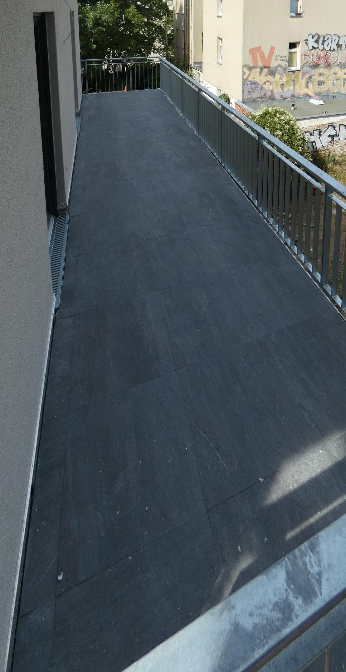 Das Bild zeigt einen Balkon. Der Balkon gehört zu einer Wohnung. Diese Wohnung wurde neu gebaut.