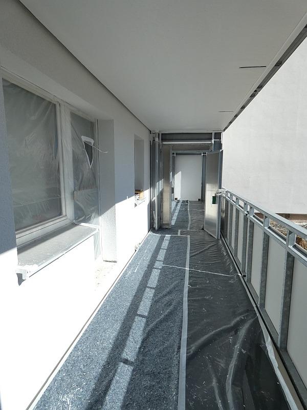 Das Bild zeigt einen Balkon. Malerarbeiten werden durchgeführt. Das Haus mit den Balkonen steht in Leipzig.