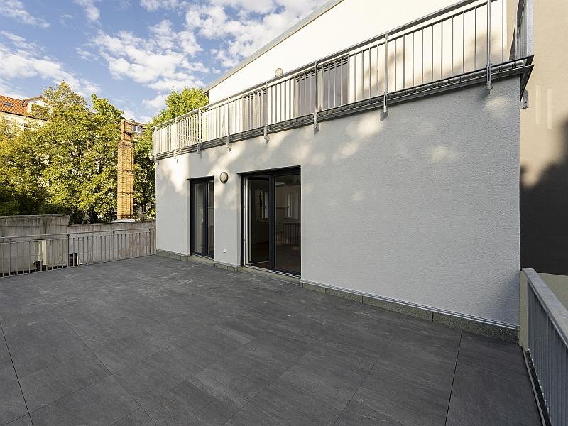 Das Bild zeigt eine Terrasse. Über die Terrasse blickt man auf ein Wohnhaus. Das Wohnhaus hat viele Terrassen. Das Wohnhaus heißt Südterrassen. Die Südterrassen befinden sich in Leipzig.