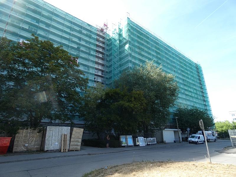 Das Bild zeig gelieferte Baustoffe. Sie stehen vor der eingerüsteten Fassade. Hier wird die Außenwand saniert.