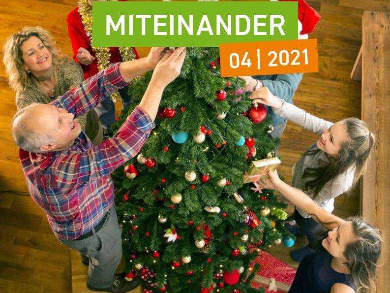 Glückliche Familie schmückt einen Weihnachtsbaum als Titelmotiv für die weihnachtliche Ausgabe der Mitgliederzeitschrift der Wohnungsgenossenschaft UNITAS eG