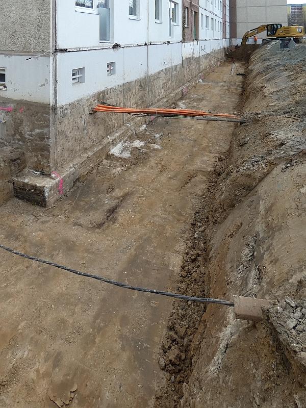 Das Bild zeigt einen Graben. Die Kellerwand von einem Haus ist zu sehen. Die soll abgedichtet werden. Dann werden Fundamente gebaut.