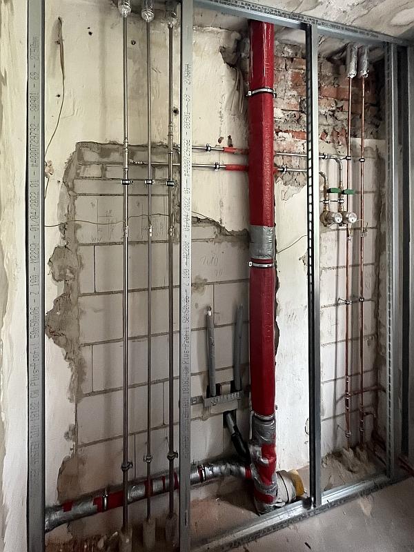 Das Bild zeigt viele Rohre vor einer Wand. Die Rohre gehören in das Bad einer Wohnung. Die Rohre wurden erneuert.