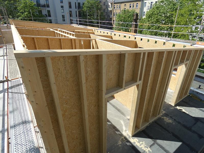 Auf dem Bild sieht man eine Holzkonstroktion. Die Holzkonstruktion bildet eine Wohnung. Sie steht auf dem Dach eines kleinen Hauses.