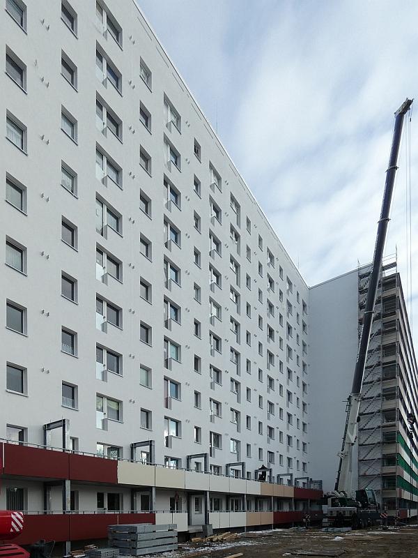 Das Bild zeigt ein Wohnhaus. Vor dem Wohnhaus steht ein Kran. Der Kran montiert Balkone. Das Wohnhaus steht in Leipzig.