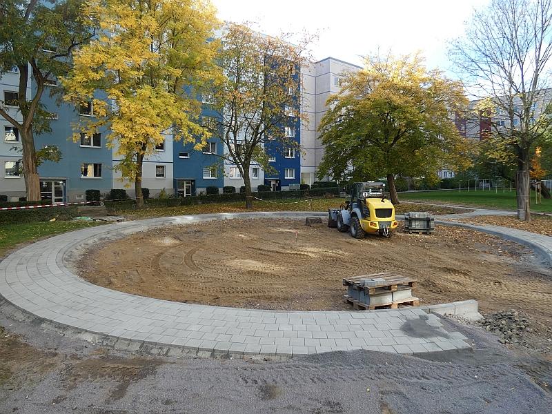 Das Bild zeigt den Bau eines Sandkastens. Der Sandkasten ist im Innenhof. Der Innenhof wird von Wohngebäuden umschlossen.