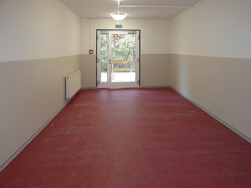 Das Bild zeigt einen Flur. Der Flur ist der Zugang zu einem Wohnhaus. Der Flur wurde neu gestrichen. Im Flur gibt es neuen Fußbodenbelag. Der Flur hat neue Lampen bekommen.